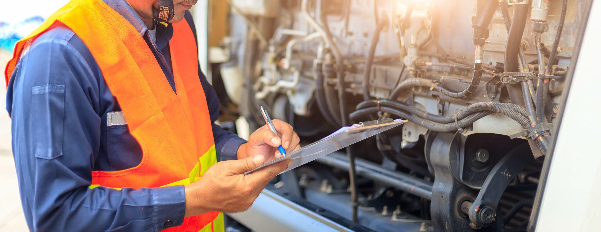 Technician inspecting an engine with a clipboard