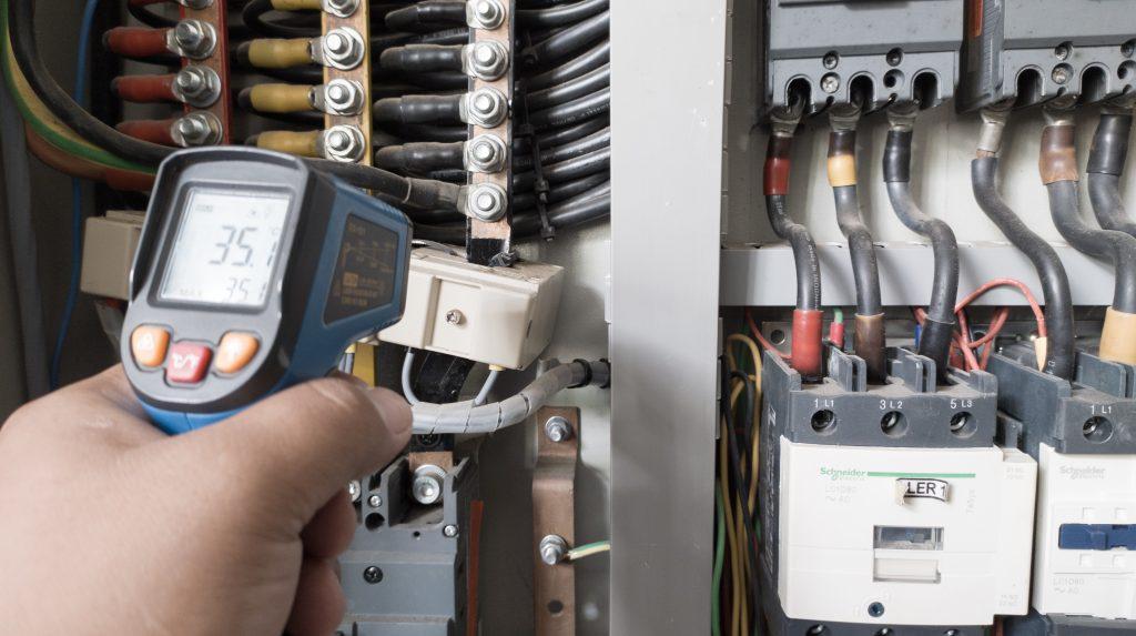 Technician checking the temperature of a wire with a heat gun